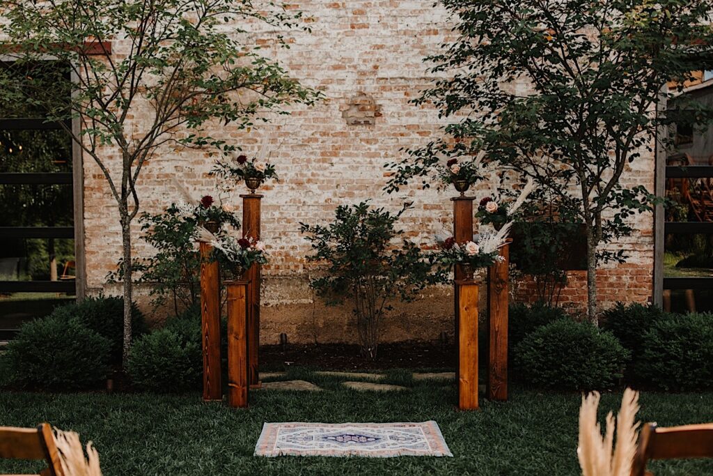 A ceremony space in front of a brick wall decorated with flowers before a wedding ceremony