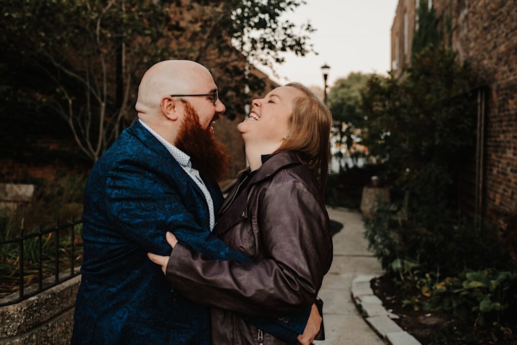 A couple hug, smile and laugh with one another while walking down a path photographed by a Chicago engagement photographer