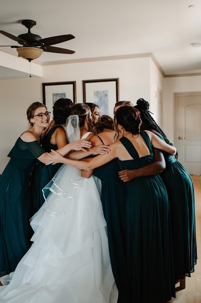 A bride receives a group hug from her 7 bridesmaids after they see her for the first time