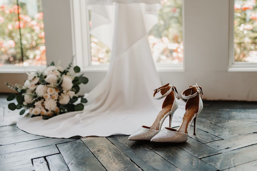 Detail photo of heels, a wedding dress, and a bouquet on the floor of a getting ready space, photographed by a Central Illinois wedding photographer