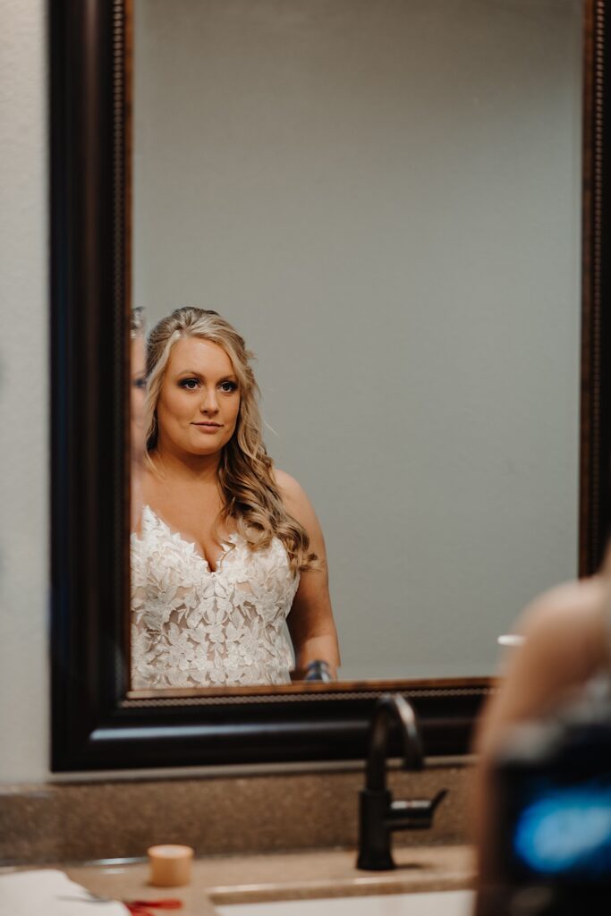 A bride in a mirror looking at herself as she gets ready for her wedding day