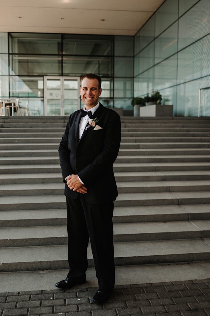Portrait of a groom standing on a set of stairs smiling at the camera