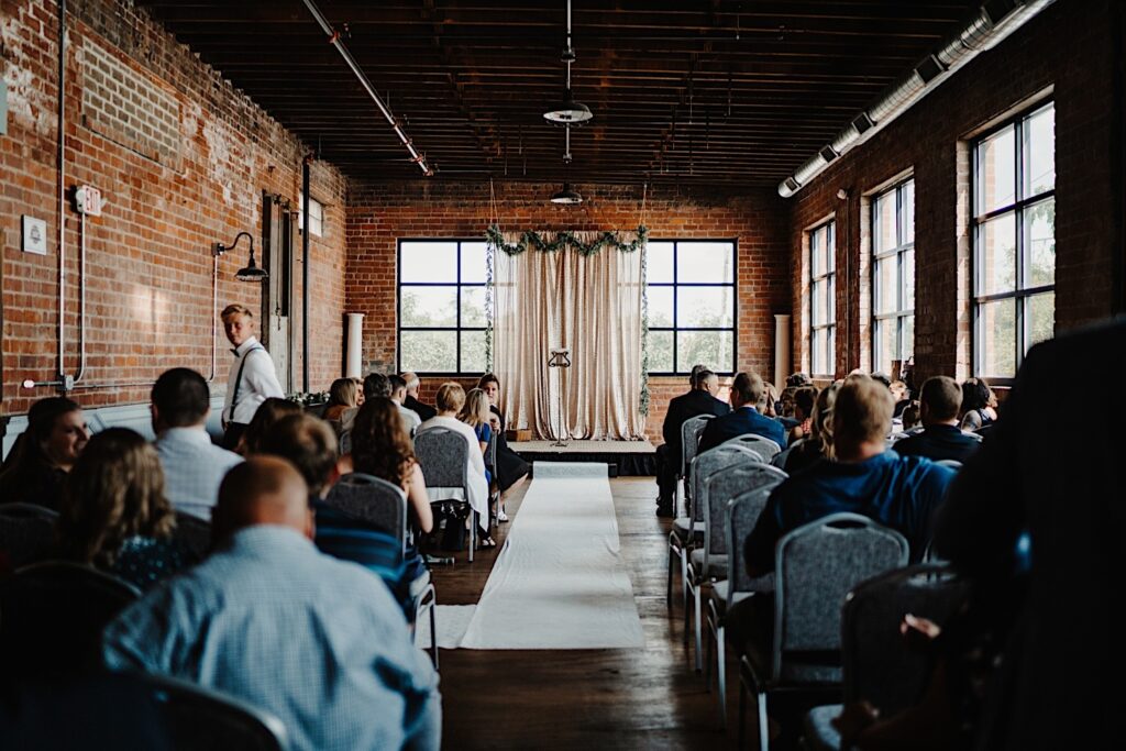 The indoor ceremony area of Stardust in Davenport decorated for a wedding ceremony with guests seated on either side of the aisle
