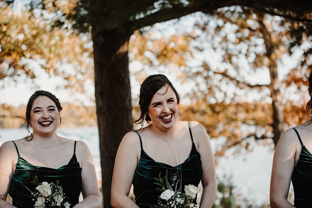 A bridesmaid laughs while standing next to another bridesmaid as the two are prep for the wedding ceremony to begin