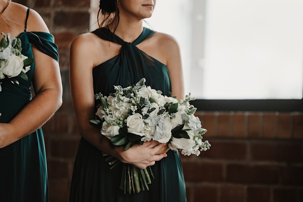 Shoulder down photo of a bridesmaid holding a flower bouquet and looking to her right