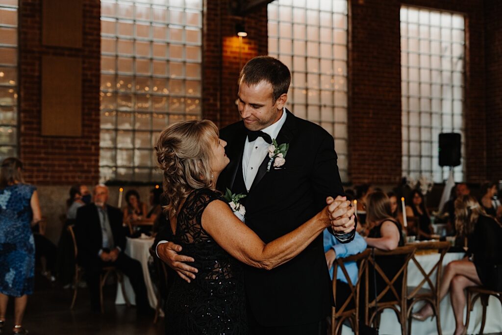A groom smiles at his mother who he is dancing with during his indoor wedding reception at Stardust in Davenport