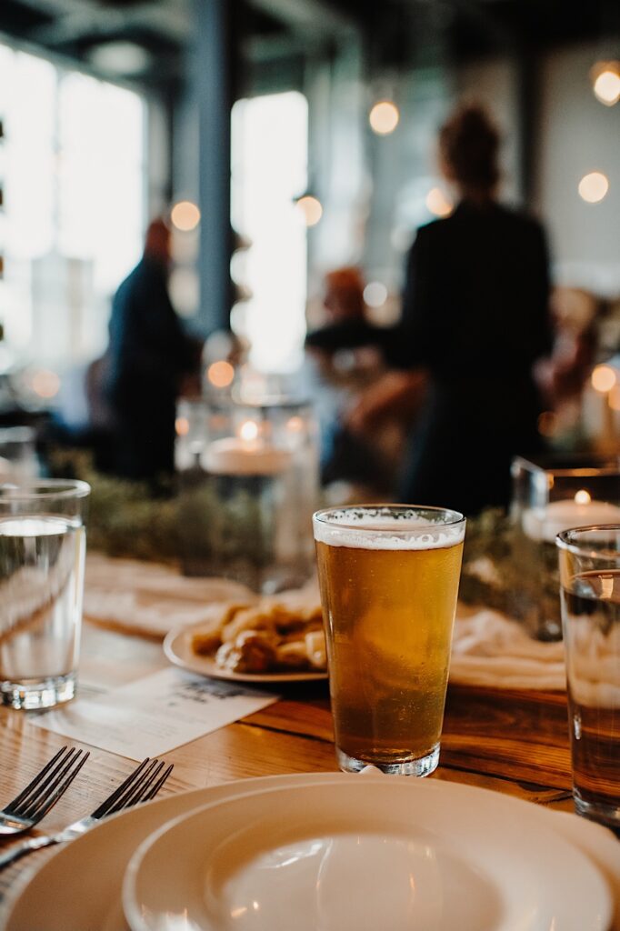 A beer in a glass sits on a table during a wedding reception