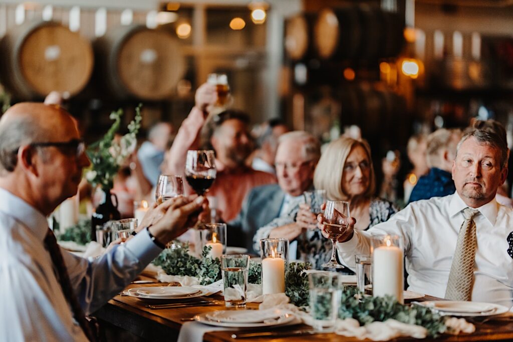 Guests of a wedding reception at Destihl Brewery's indoor venue space raise their glasses during a speech
