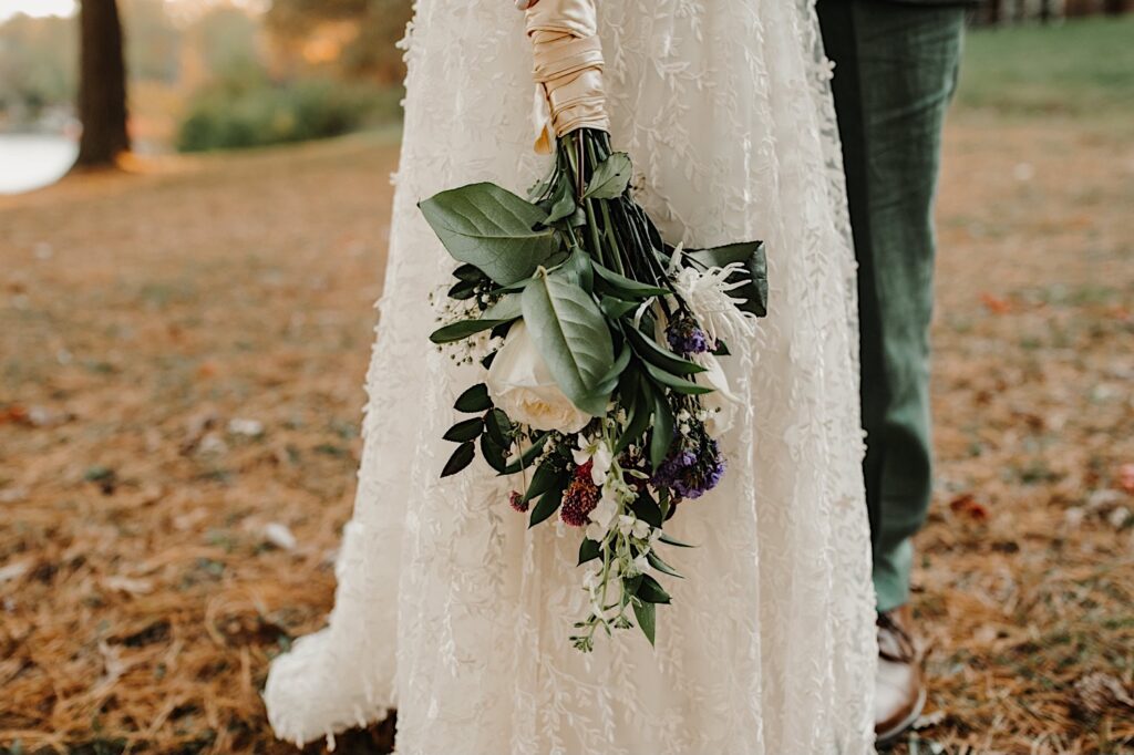 Detail photo of a flower bouquet being held by a bride next to her dress