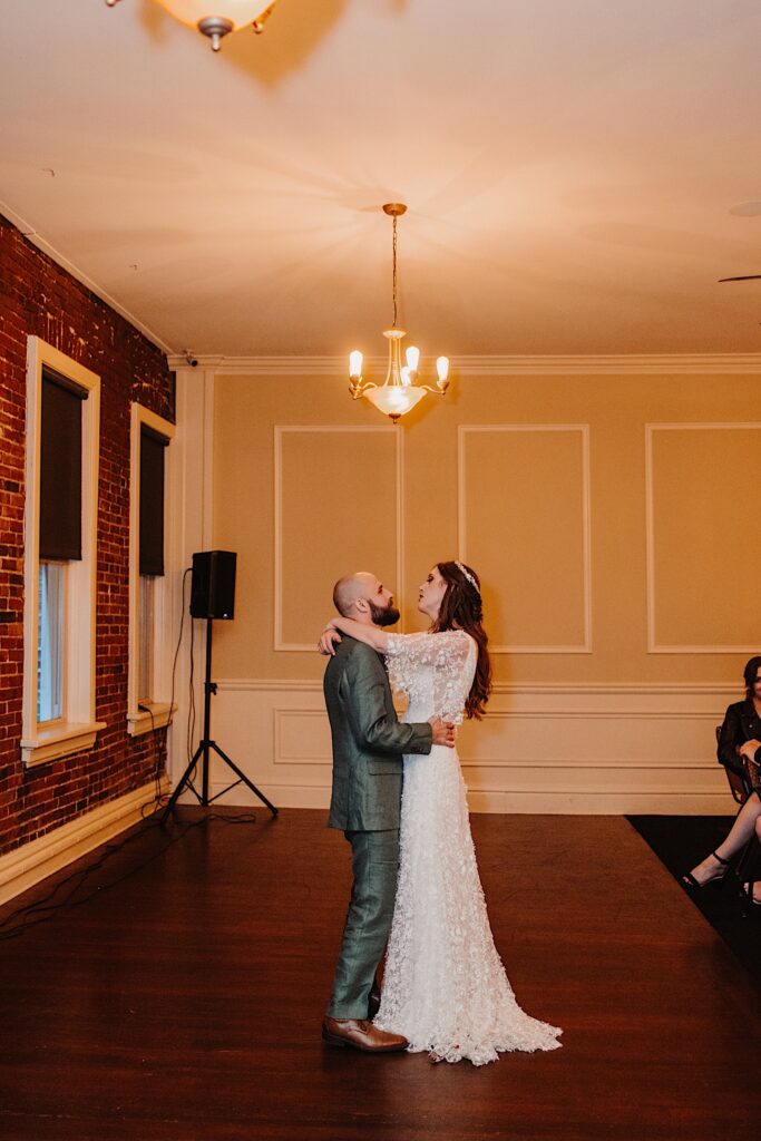 A bride and groom share their first dance together during their indoor wedding reception