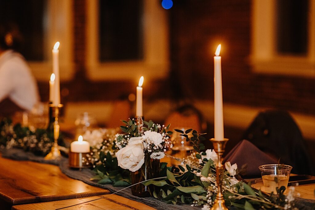 A table decorated for a wedding with white flowers, candles, and other greenery