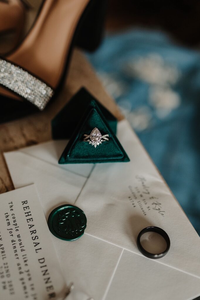 A wedding ring sits on an envelope with another wedding ring sitting in a box also on the envelope