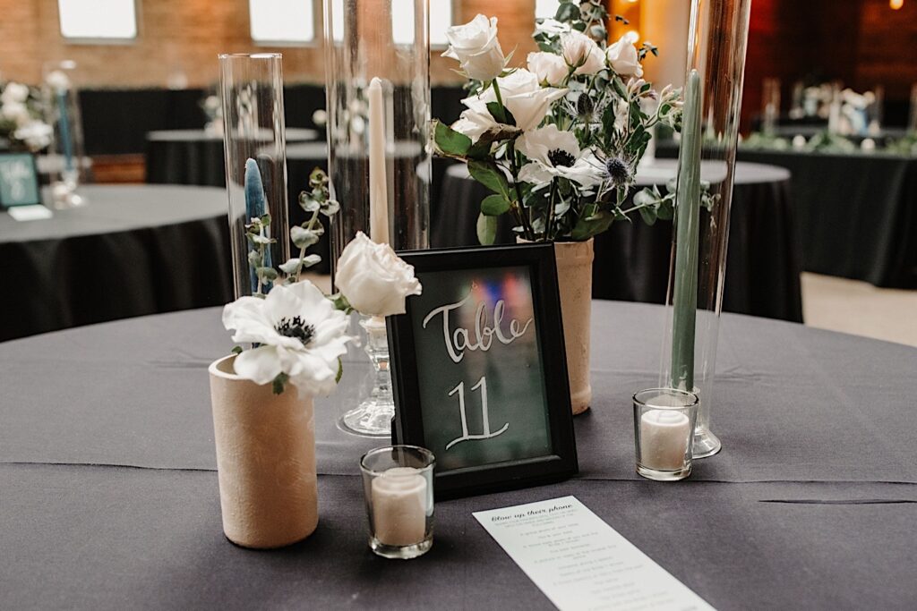 A table decorated for a wedding with candles, glassware, flowers, and a picture frame that reads "Table 11"