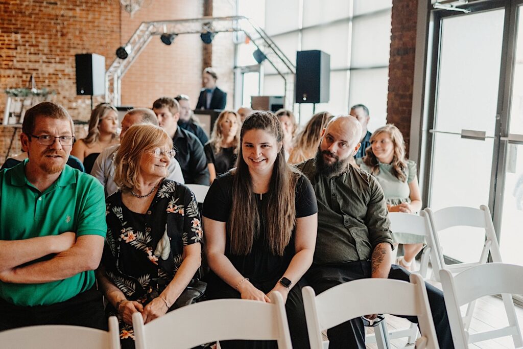 Guests of a wedding ceremony at Reality on Monroe are seated and look at the camera while they wait for the ceremony to begin