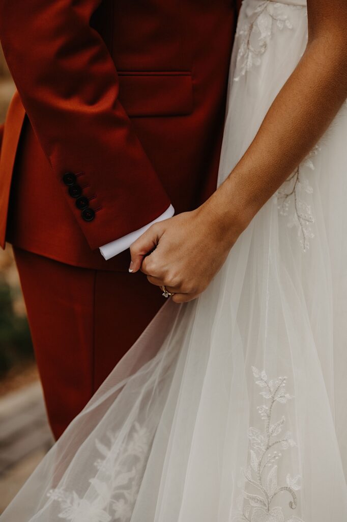 Close up photo of a bride and groom's hands holding one another