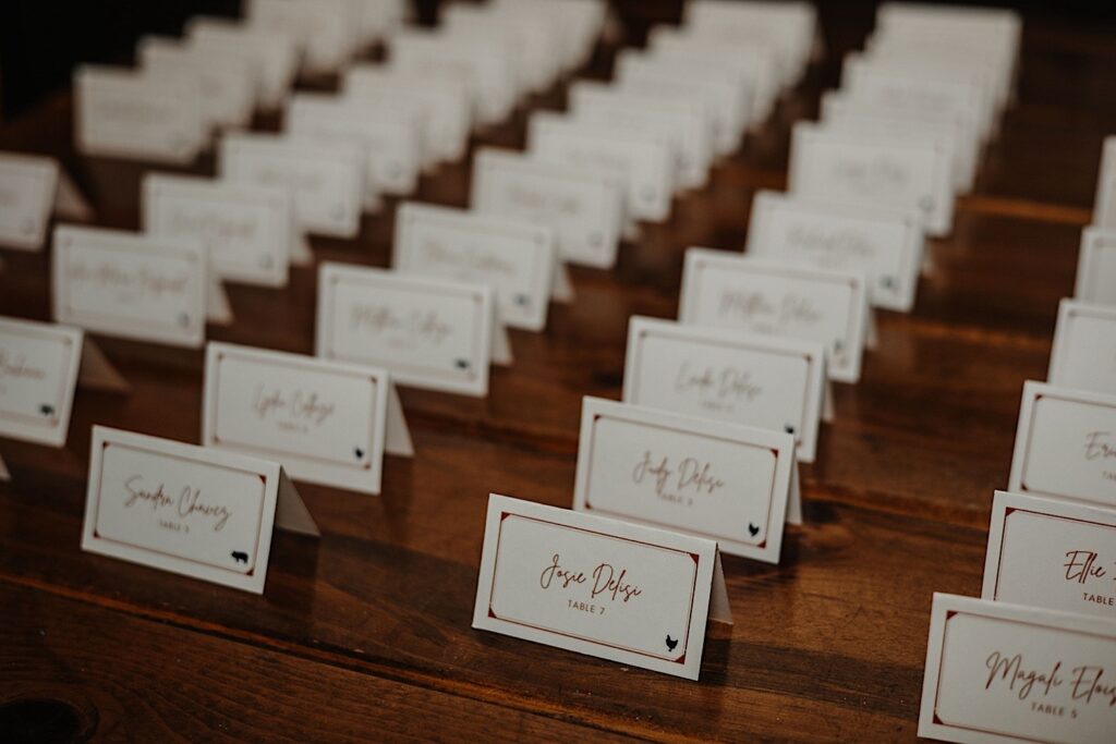 Name tags with table numbers sit in rows on a table for guests of a wedding reception