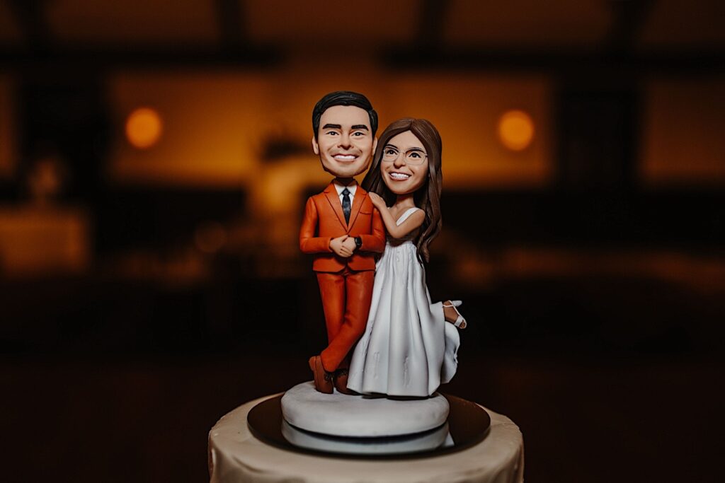 A bobblehead figuring of the bride and groom sits atop a cake