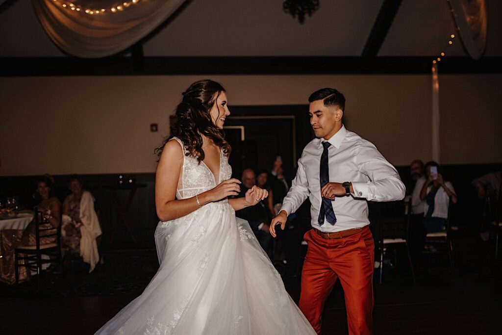 A bride and groom share their first dance as guests watch during their indoor fall wedding reception at Mistwood Golf Club