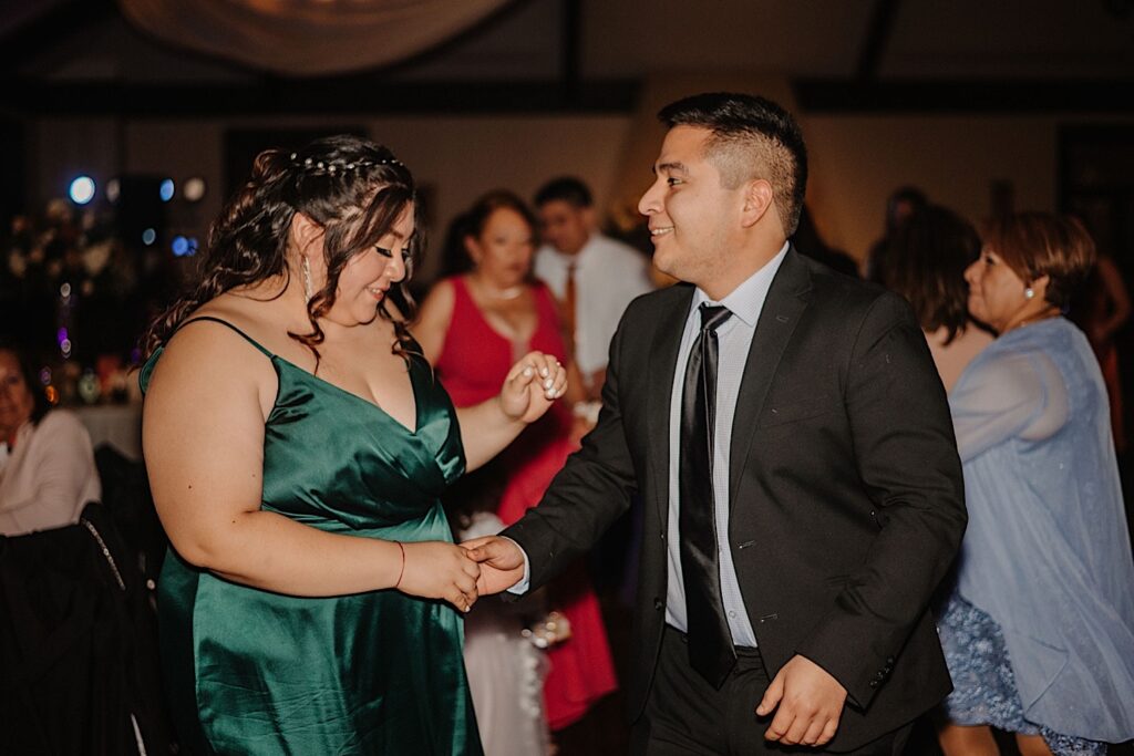 Guests of an indoor fall wedding reception at Mistwood Golf Club dance with one another