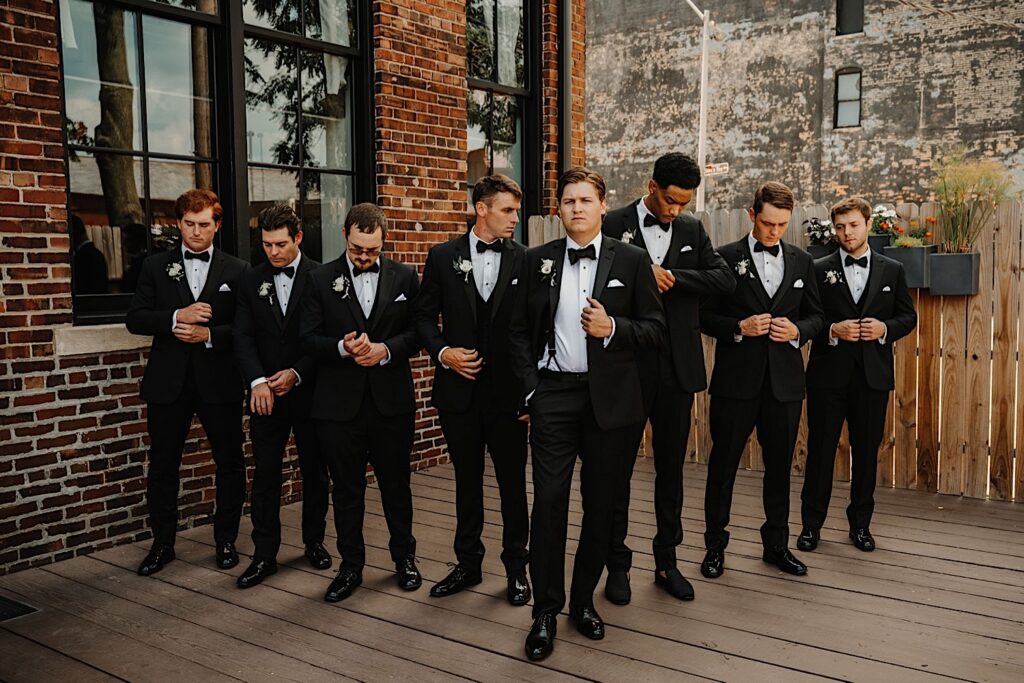 A groom with his groomsmen pose together outside of Venue CU in Champaign for portraits during the groom's wedding day