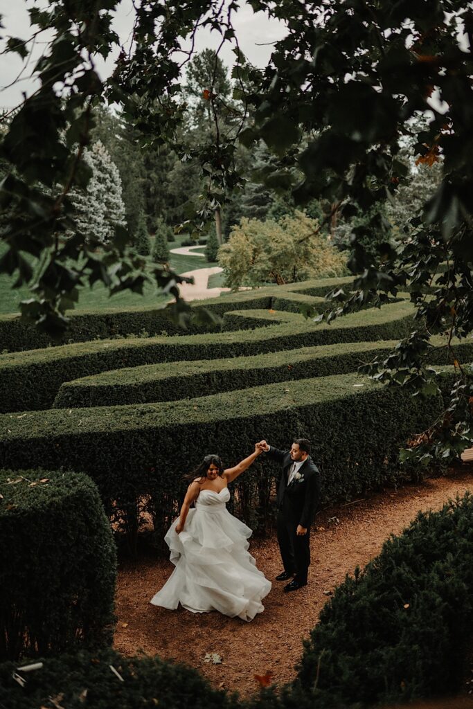 Aerial photo of a bride and groom dancing in a hedge maze on a cloudy day