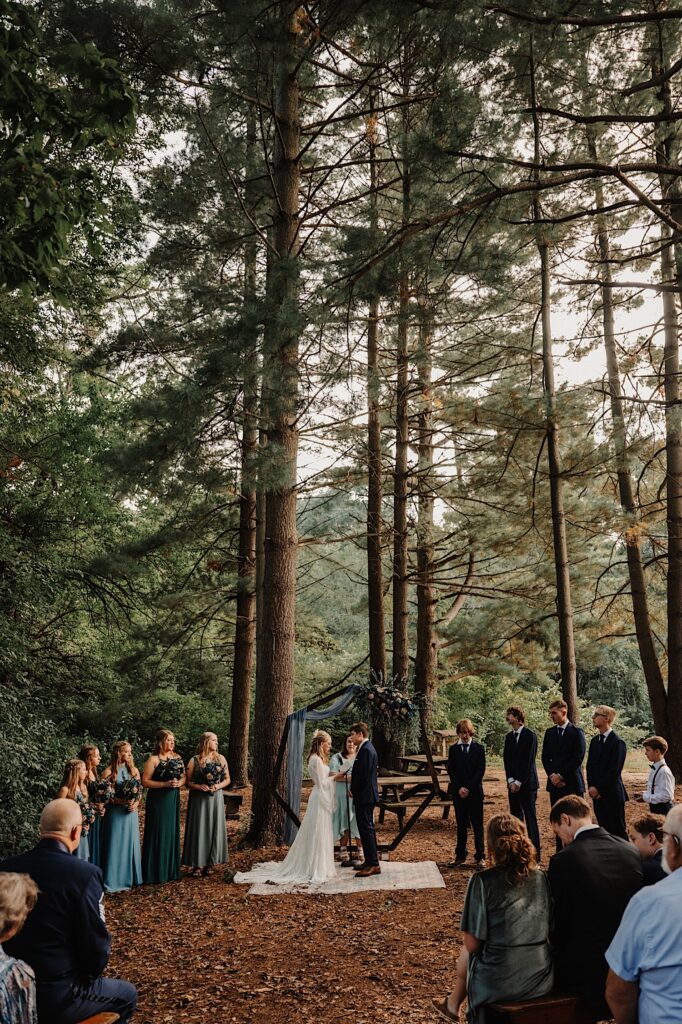 A bride and groom stand outside surrounded by their guests during their outdoor wedding ceremony