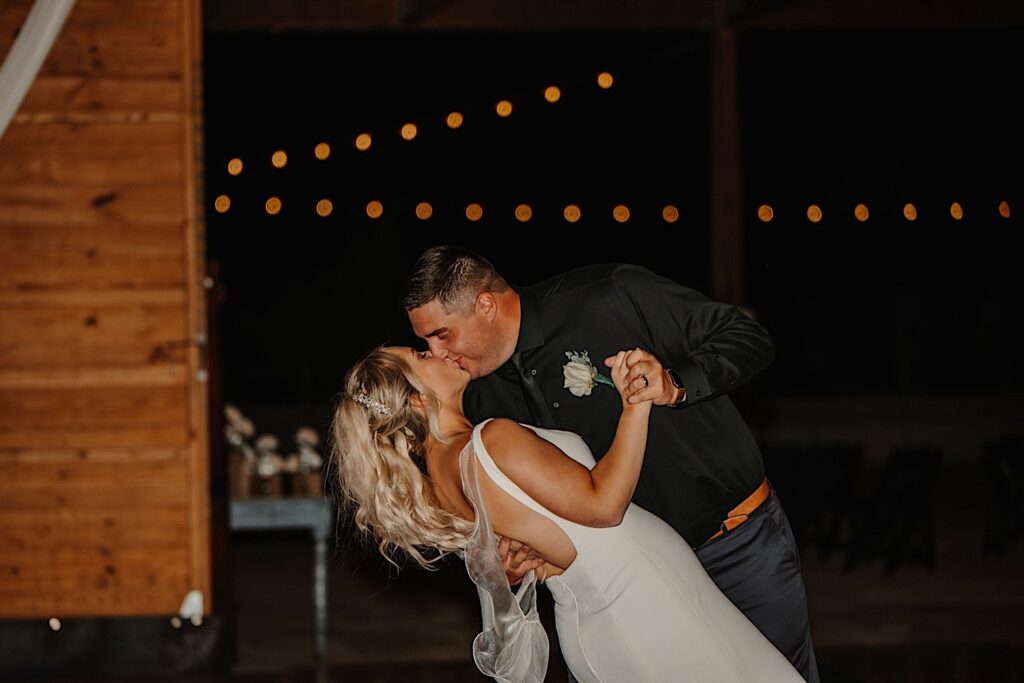 A bride and groom kiss during their indoor wedding reception as the groom dips the bride while they dance, photo taken by a Central Illinois Wedding Photographer