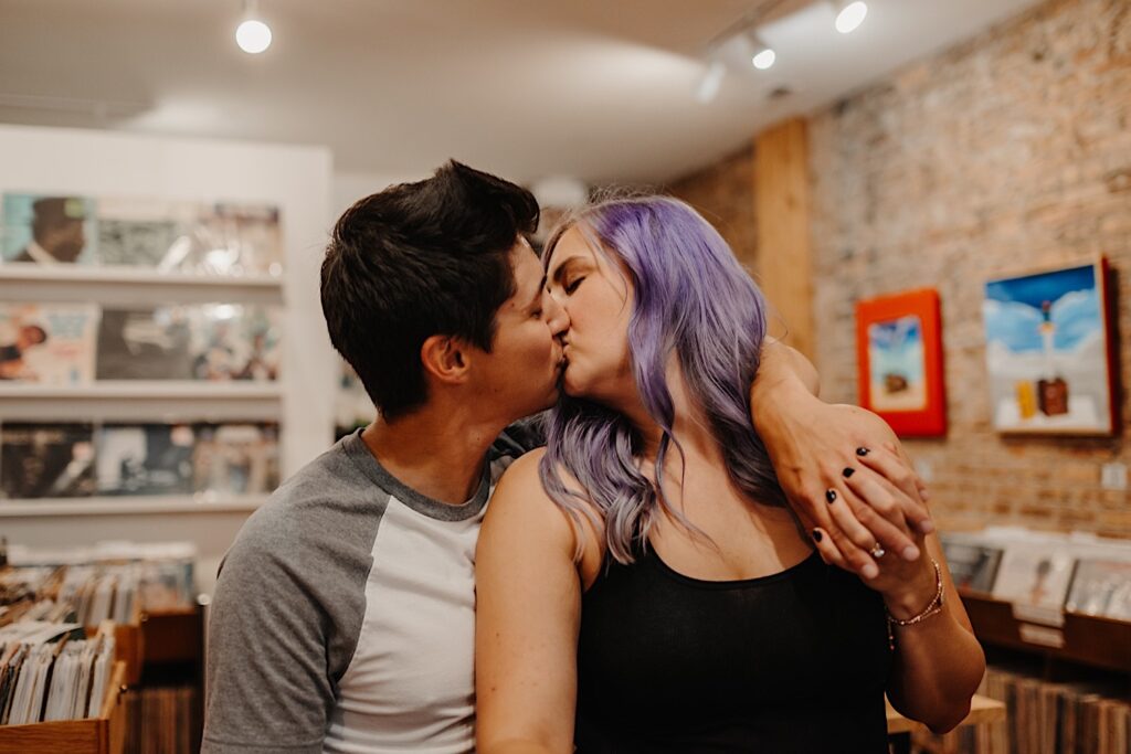 A couple kiss one another for their engagement photos while inside of a record store in Chicago 