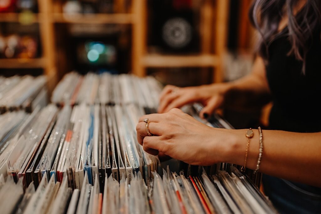 Close up photo of a woman's hands looking through a display of vinyl records