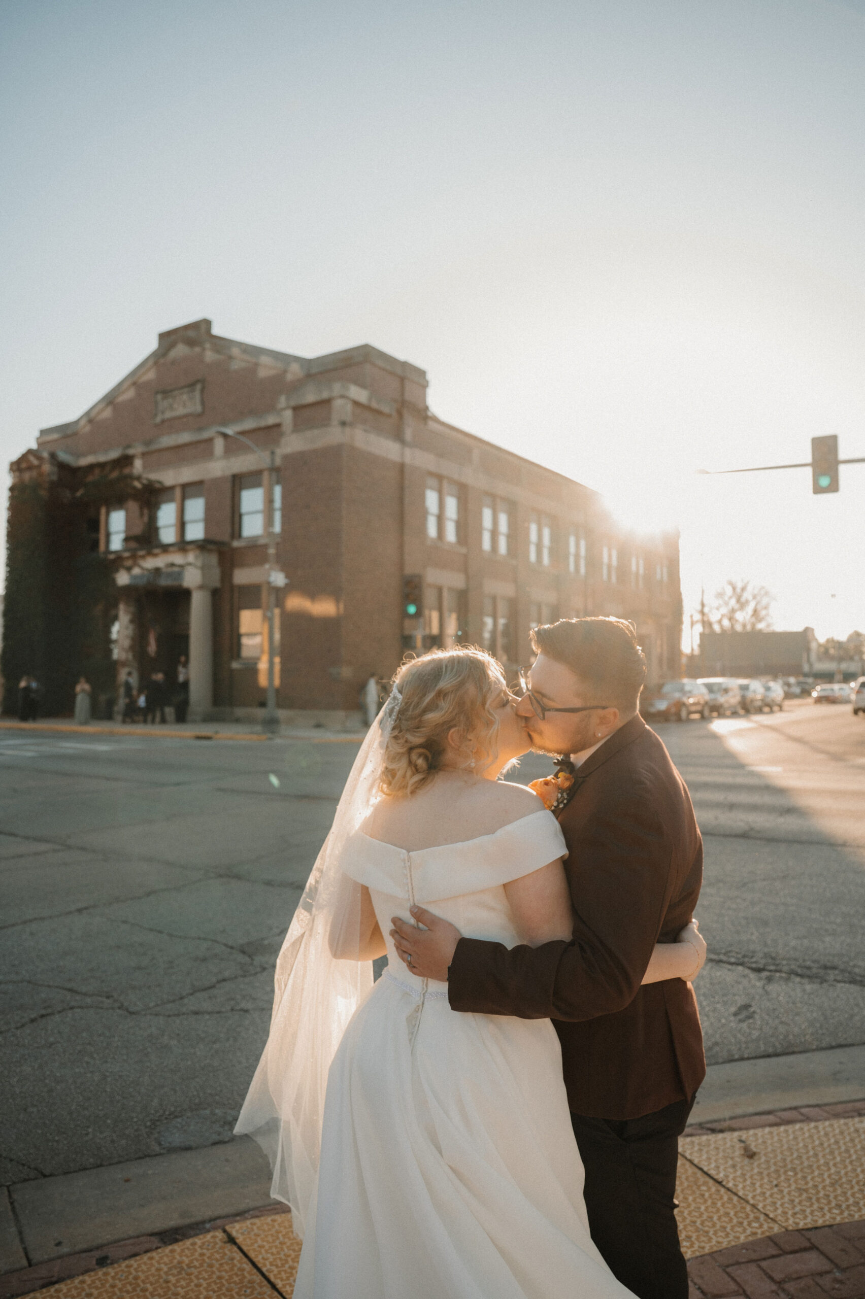 wedding couple stands at the corner of the silver fox in streator il during sunset and kisses